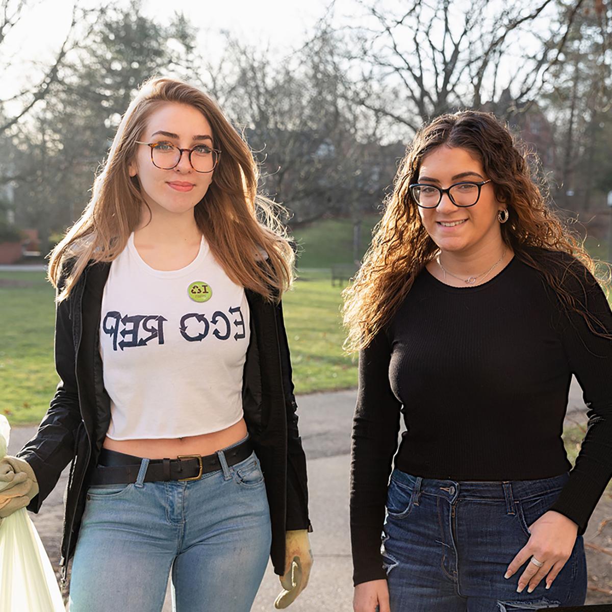 Photo of two students, one wearing an Eco Rep shirt, pick up litter on Shadyside Campus